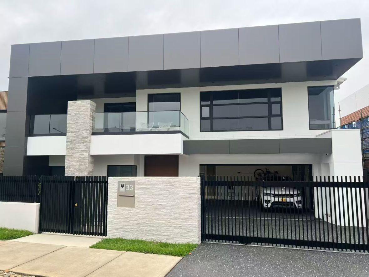 Two-storey home with dark cladding and black-framed aluminium glazing